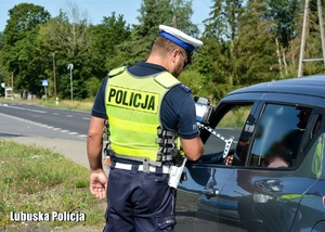 Policjant podczas kontroli drogowej przy pojeździe.