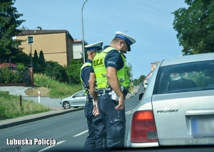 Policjanci podczas kontroli drogowej przy pojeździe.