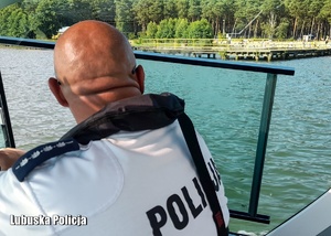 Policjant płynący motorówka po jeziorze.