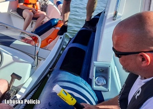 Policjant podczas sprawdzania stanu trzeźwości osób na łodzi.
