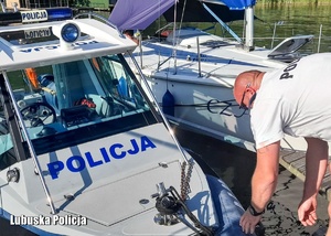 Policjant odczepia linę od łodzi.