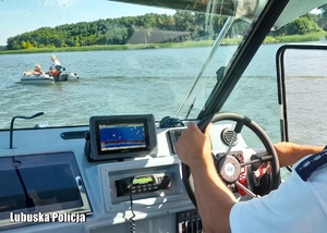 Policjant płynie motorówka po jeziorze.