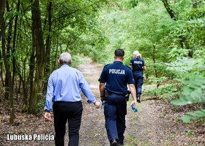 Mężczyzna i policjanci w akcji poszukiwawczej w lesie
