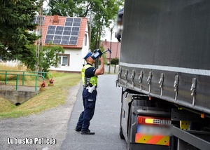 Policjant drogówki pokazuje prędkość zarejestrowaną na urządzeniu pomiarowym kierowcy ciężarówki.