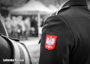 Czarno białe zdjęcie strażaka z wyszytym godłem Polski.
