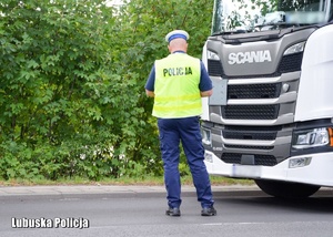 Policjant drogówki zatrzymuje do kontroli pojazd ciężarowy.