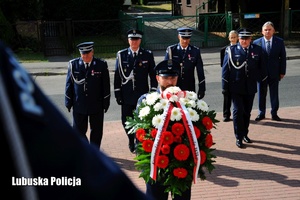 Policjanci składają kwiaty przed tablicą pamiątkową.