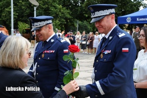 Policjant wręcza róże wyróżnionej kobiecie.