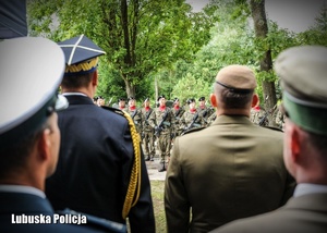 Funkcjonariusze, a naprzeciwko nich żołnierze stojący w szeregu podczas uroczystości.
