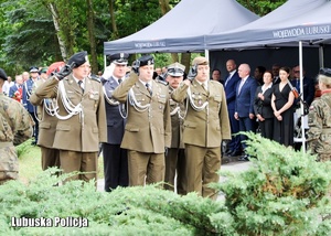 Żołnierze oddają honory przed pomnikiem.