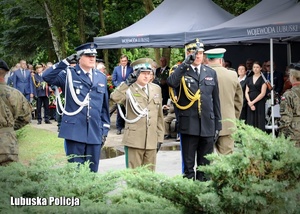 Komendanci służb mundurowych oddają honory przed pomnikiem.