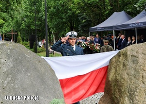Funkcjonariusz Inspekcji Transportu Drogowego oddaje honory przed pomnikiem.