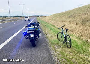 Policyjny motocykl i rower na poboczu na drodze ekspresowej.