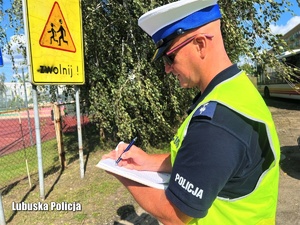 Policjant sprawdza oznakowanie przy szkołach i przedszkolach