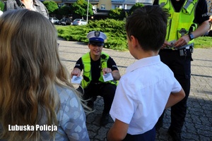Policjantka ruchu drogowego rozdaje uczniom odblaski