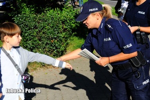 policjantka rozdaje ulotki dzieciom