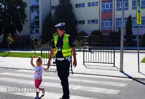 Policjant przeprowadza dziecko przez przejście