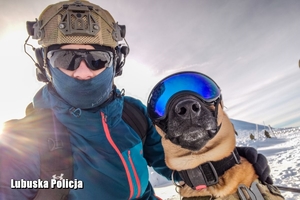 Policjant ze swoim psem służbowym zimą w górach na ćwiczeniach