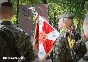 Sztandar wojskowy na tle pomnika.