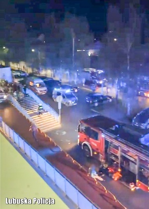 Pojazdy Policji i Straży Pożarnej przed budynkiem szpitala.