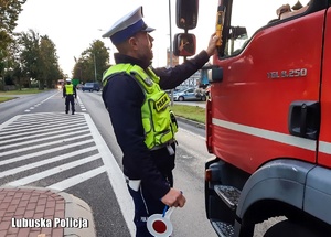 Policjant ruchu drogowego kontroluje stan trzeźwości kierowców na drodze.
