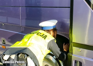 Policjantka drogówki sprawdza opony w autokarze.