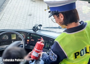 Policjantka kontroluje gaśnicę w autokarze.