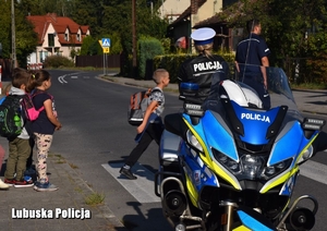 policjantka uczy dzieci przechodzić przez drogę