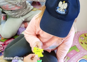 Dziecko w policyjnej czapce otrzymuje element odblaskowy.