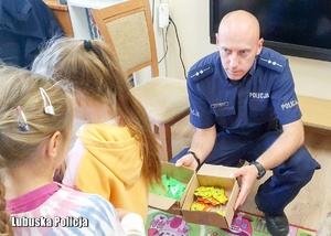 Policjant rozdaje dzieciom elementy odblaskowe.