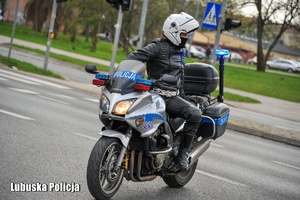policyjny motocyklista podczas jazdy drogą.