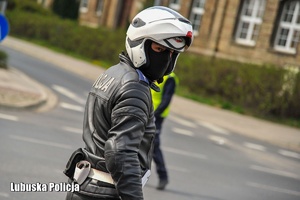 Policyjny motocyklista idzie po jezdni.