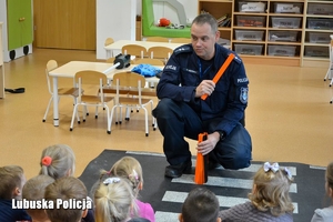 Policjant rozmawia z dziećmi o odblaskach