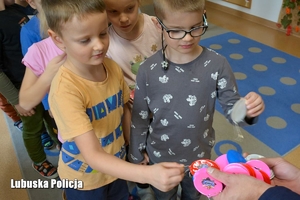 Dzieci otrzymują odblaski od policjanta