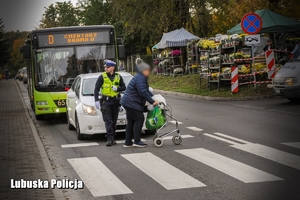 policjant pomaga kobiecie przejść przez przejście dla pieszych