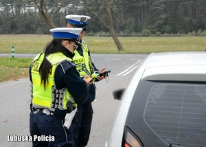 Policjanci drogówki podczas przeprowadzania kontroli drogowej pojazdu osobowego.