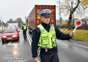Policjant drogówki zatrzymuje pojazd do kontroli drogowej -  w tle inne pojazdy.