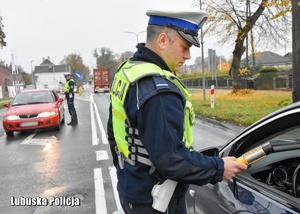 Policjant drogówki sprawdza trzeźwość kierującego samochodem.