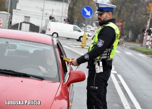 Policjant drogówki sprawdza trzeźwość kierującego samochodem.