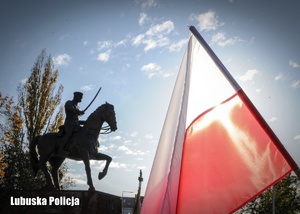 Flaga Polski, a w tle pomnik Marszałka Józefa Piłsudskiego.
