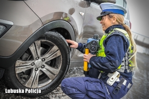 Policjantka drogówki podczas sprawdzenia stanu technicznego pojazdu.