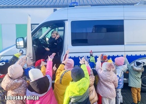 Policjantka pokazuje dzieciom radiowóz policyjny i jego wyposażenie.