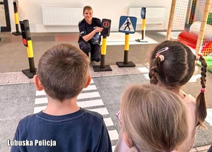 Policjantka tłumaczy dzieciom zasady ruchu drogowego.