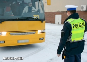 Policjant drogówki sprawdza oświetlenie autobusu.