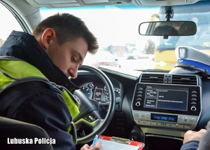Policjant podczas sporządzania dokumentacji z kontroli autokaru.