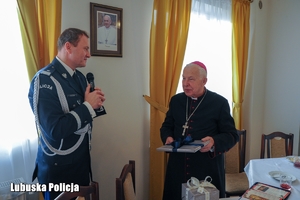 Komendant Wojewódzki Policji wręcza prezent świąteczny biskupowi.
