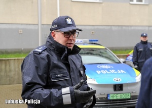 Zastępca Komendanta Wojewódzkiego Policji, a w tyle zaparkowany radiowóz.