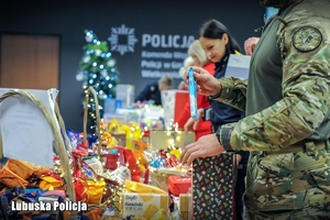 Policjanci i pracownicy Policji podczas pakowania prezentów świątecznych.