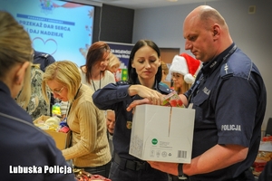 Policjanci i pracownicy Policji podczas pakowania prezentów świątecznych.
