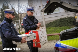 Policjanci drogówki podczas wkładania prezentów świątecznych do radiowozu.